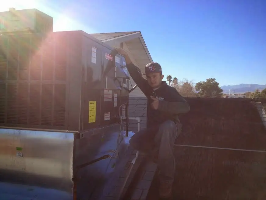 HVAC technician performing AC Tune-Up on a rooftop unit in Carencro